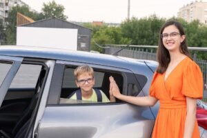 Parent waving off a child leaving for school by car